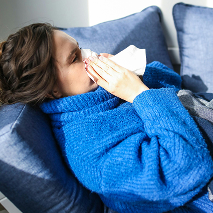 sick person sneezing into tissue