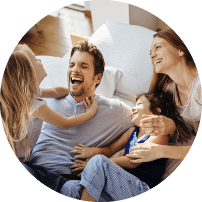 Family laughing on bed