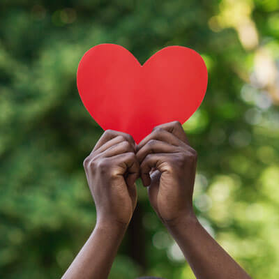 person holding a cutout cartoon heart in the air