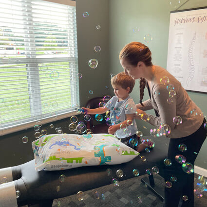 Dr Julia of Schoenherr Chiropractic with little boy blowing bubbles