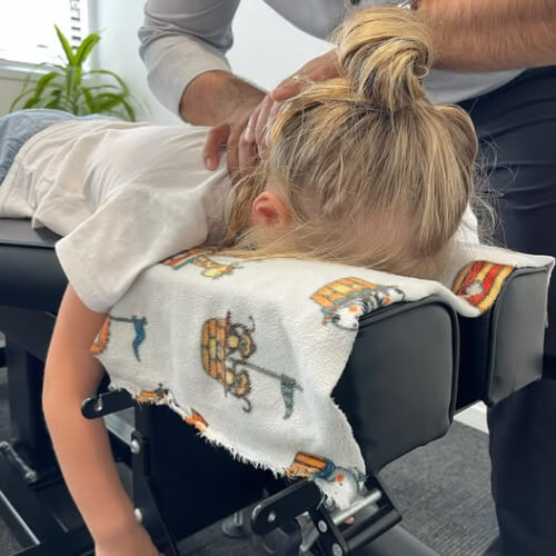Chiropractor adjusting young girl's neck