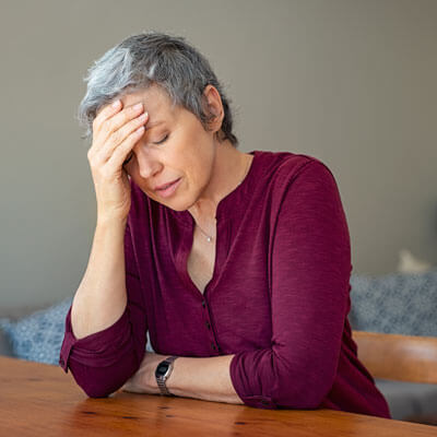 stressed woman sitting at table with hand on her head