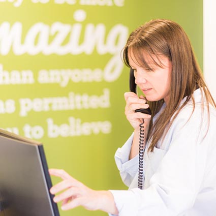 woman talking on phone working at a computer