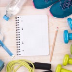Fitness equipment and blank notebook on wooden background