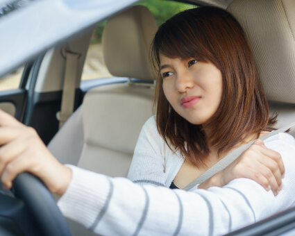 Woman with shoulder pain sitting in car