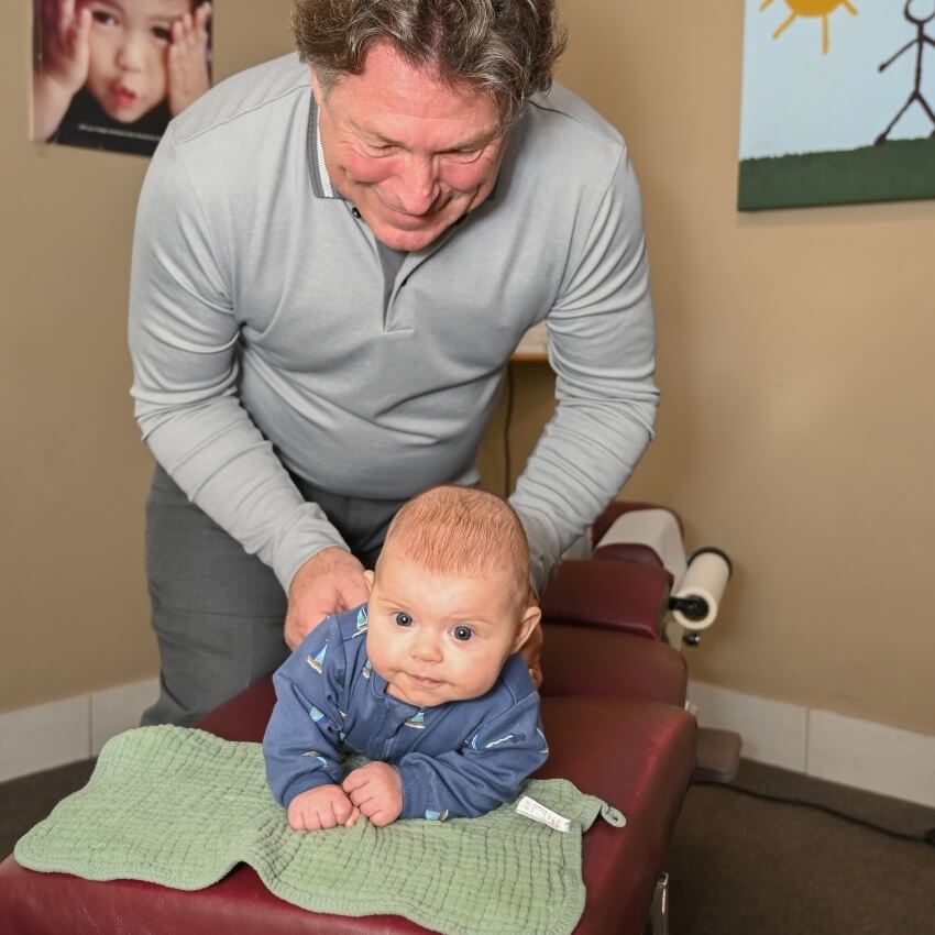 Dr Brett adjusting baby laying on table
