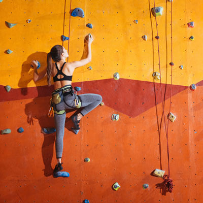 woman rock climbing on an orange wall