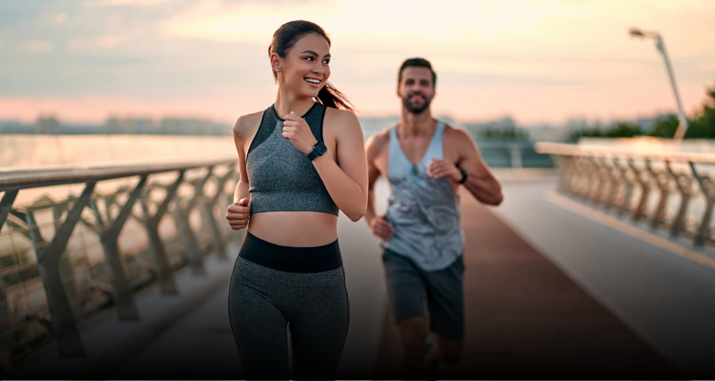 man and woman running outdoors at sunset