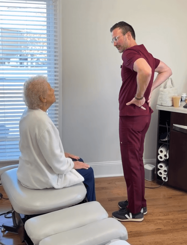 Chiropractor discussing low back pain with a seated patient at Vezendy Chiropractic in Cornelius, NC