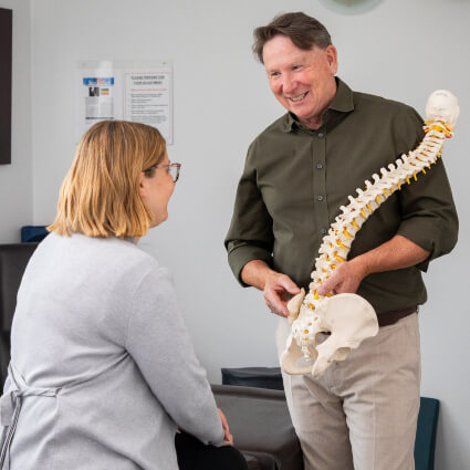 Keysborough chiropractor discussing a spine model with a patient