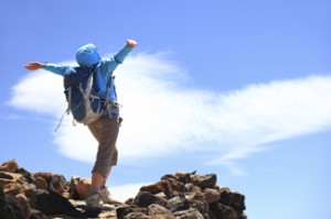 A person standing on a mountain top with their arms out-stretched.