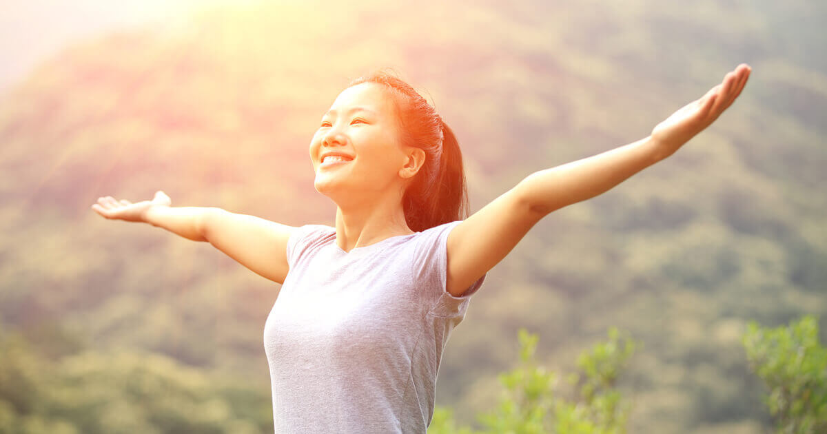 Happy woman arms outside by mountains