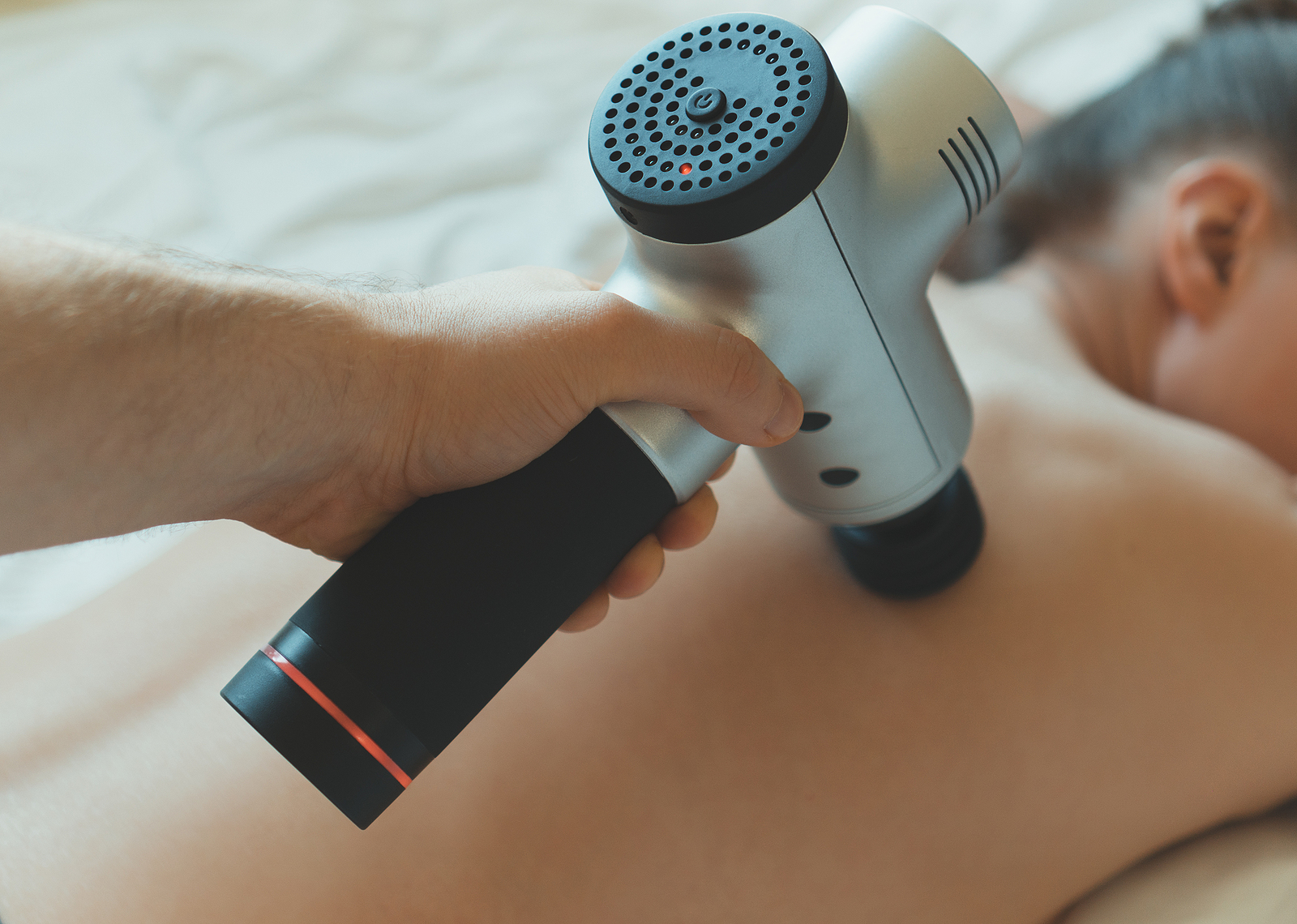 Man Massaging Woman's Back With Massaging Percussion Device. Per