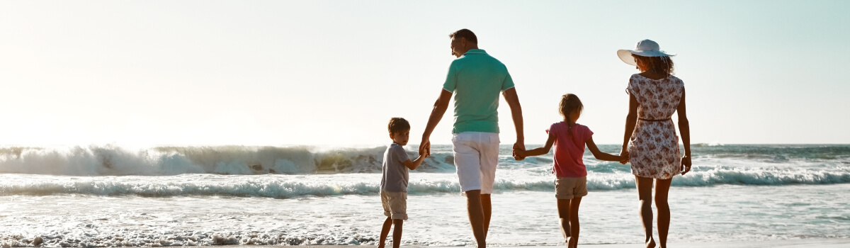 family holding hands and walking on beach