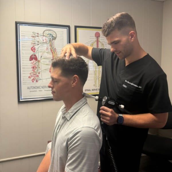 Chiropractor using tool to treat a patient