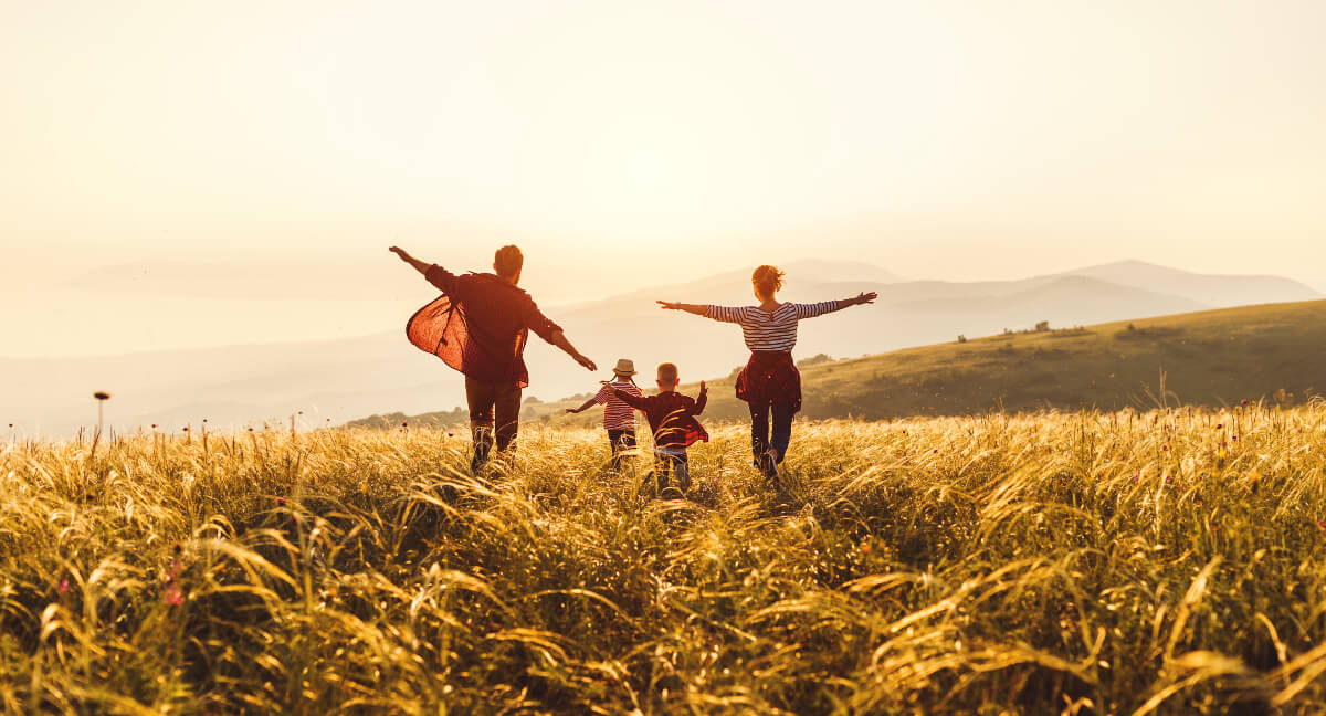 Mom and dad arms outstretched in nature with young children