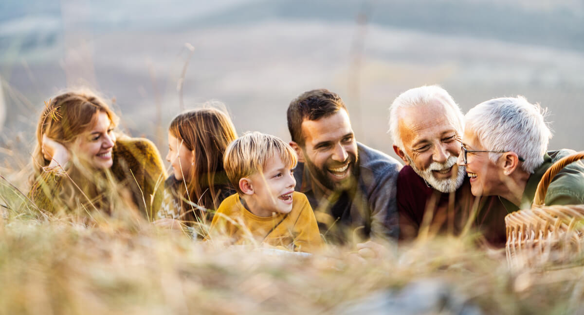 Multi-generational family lying down in field