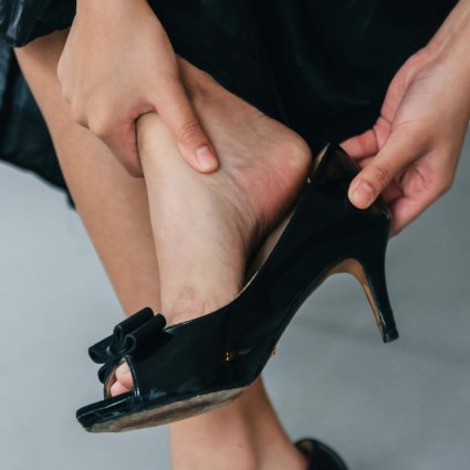 Close-up of a woman removing black high heels while seated indoors.