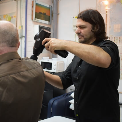 Croydon Sports Injury Clinic Ltd patient getting a shoulder massage with massage gun