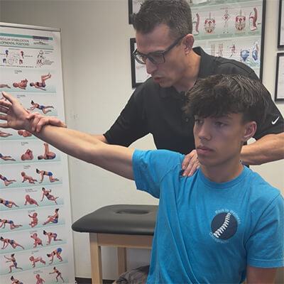 doctor adjusting teen's shoulder