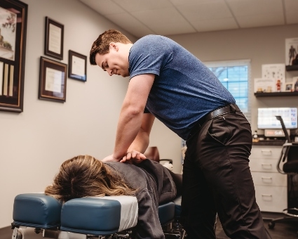 Male chiropractor adjusting female patient