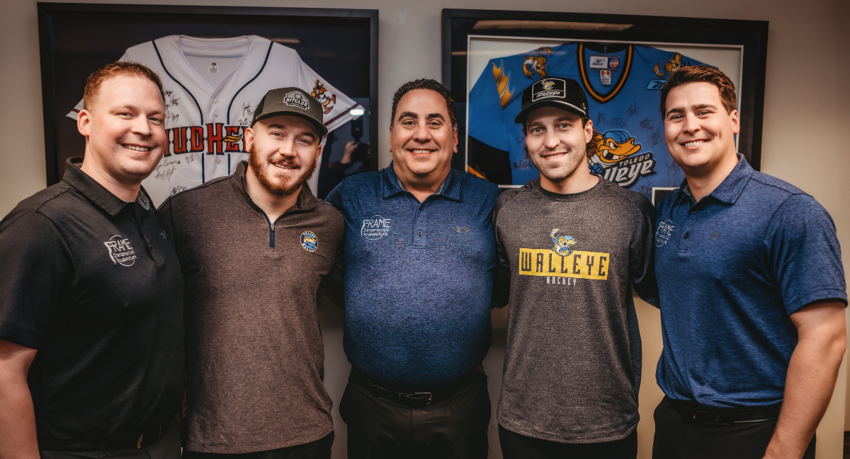 Chiropractors posing for photo with two professional athletes