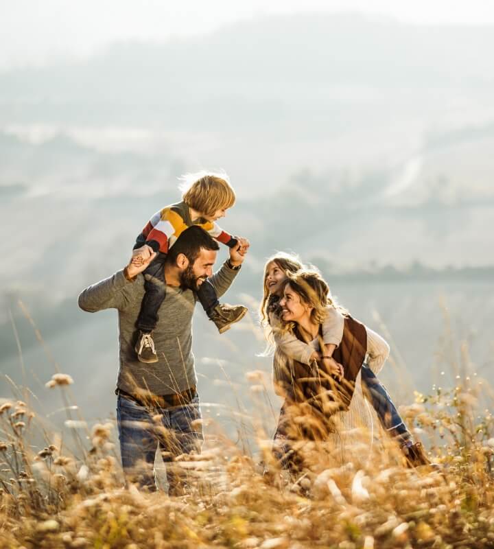 two adults and their children walking in a field