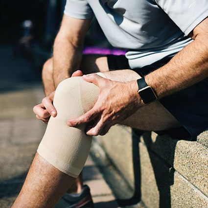 Man holding injured knee wrapped with bandage