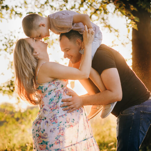 Pregnant woman embraced by husband and young child