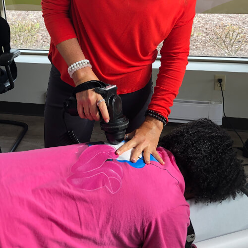 Chiropractor using tool on patient