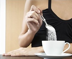 Woman pours sugar into a tea cup