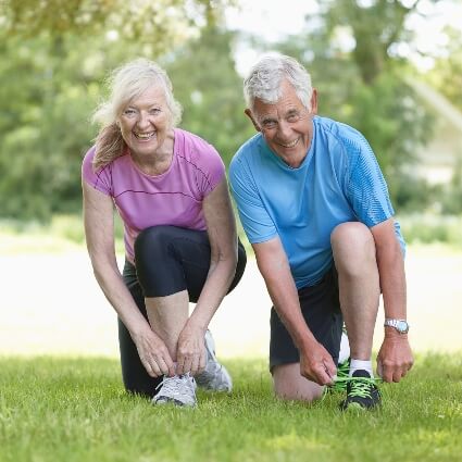 Older couple smiling while tying their shoelaces