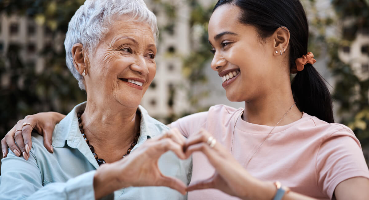 Two women making a heart shape with their hands