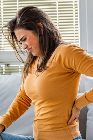 woman sitting on couch with sciatica pain