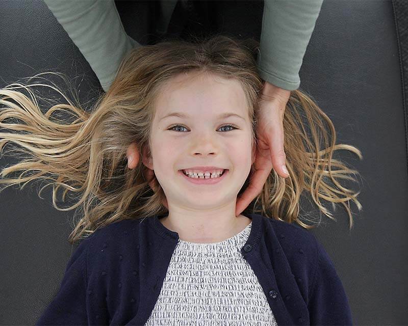 Young girl smiling while having neck adjusted