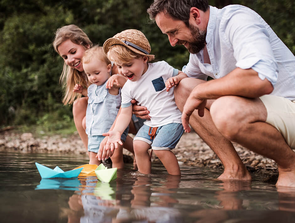 family playing paper boat at the river
