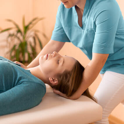 Female practitioner adjusting womans neck laying on table