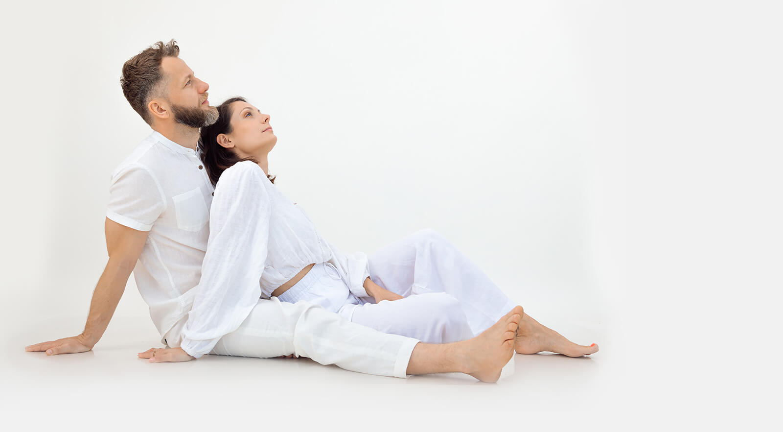 couple wearing white clothes sitting together and looking upwards
