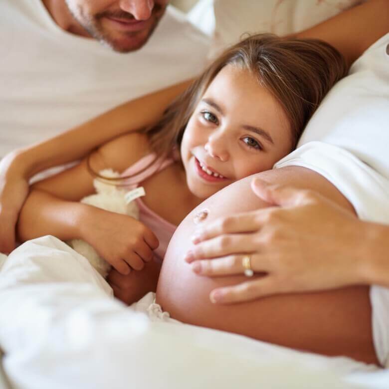 pregnant person cuddling with daughter