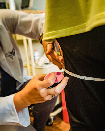 Weight loss practitioner using measuring tape on patient