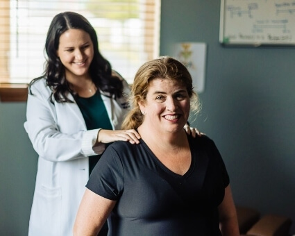 Smiling female patient receiving a shoulder adjustment