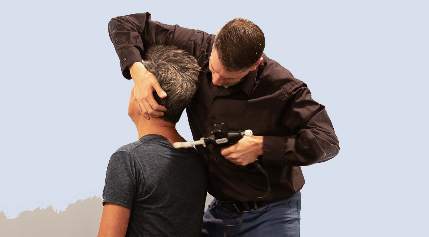 Chiropractor using tool to a patient