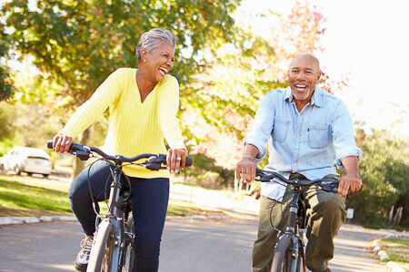 older adult couple riding bikes and laughing together