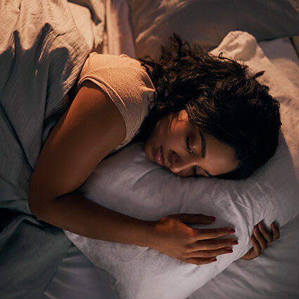 Woman on bed hugging pillow