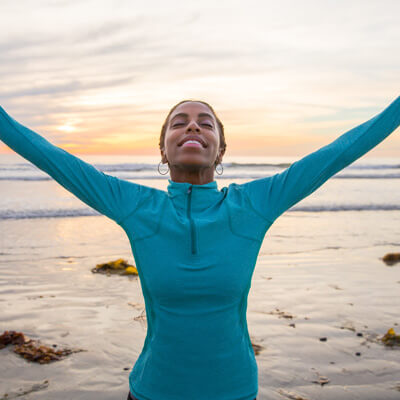 woman standing on a beach with her arms outstretched