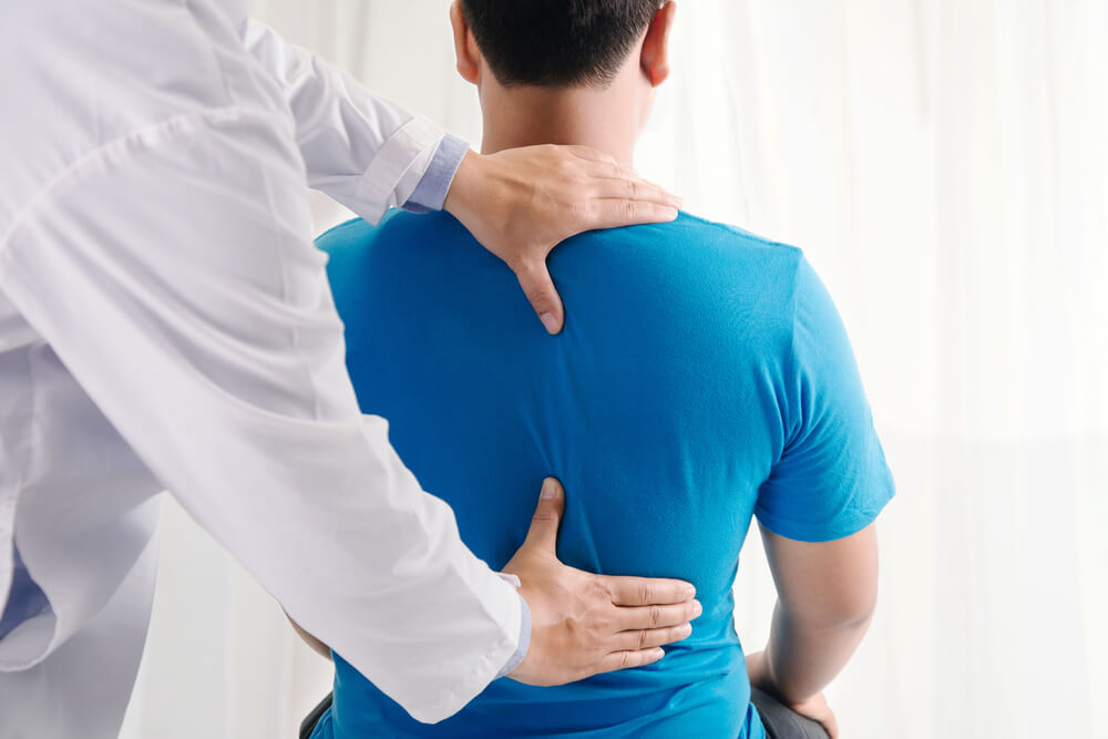 chiropractor performs treatment on man with back pain