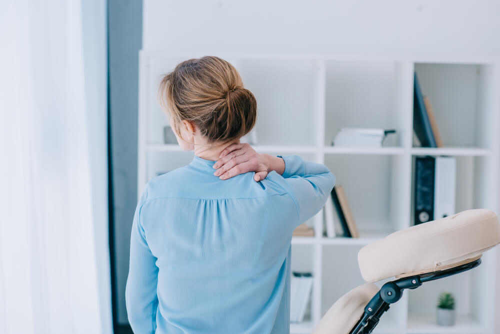 seated woman with neck pain could use chiropractic treatment