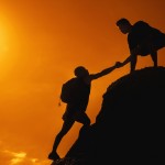 Two men climbing on mountain peak on sunset