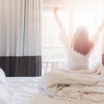 Asian women are staying in a hotel room after wake up on morning. Open the curtain in the room looking to outside view.Vintage tone.