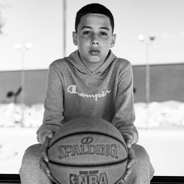 kid sitting on bench holding a basketball